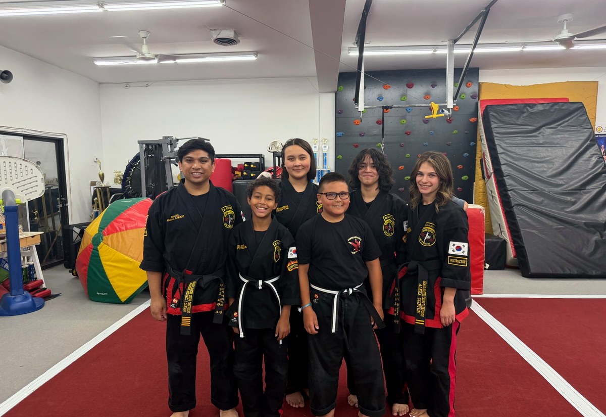 A martial arts team posed together in black uniforms.