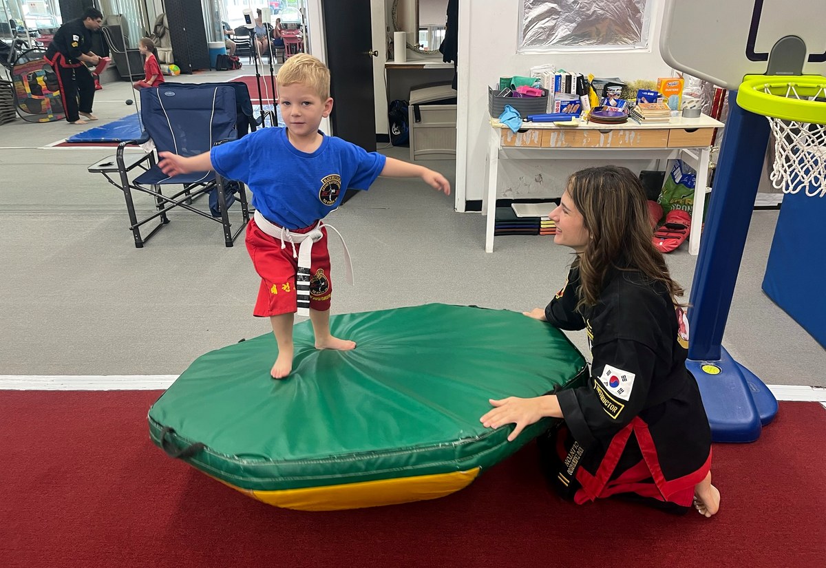 A student practicing a balance activity with instructor support.